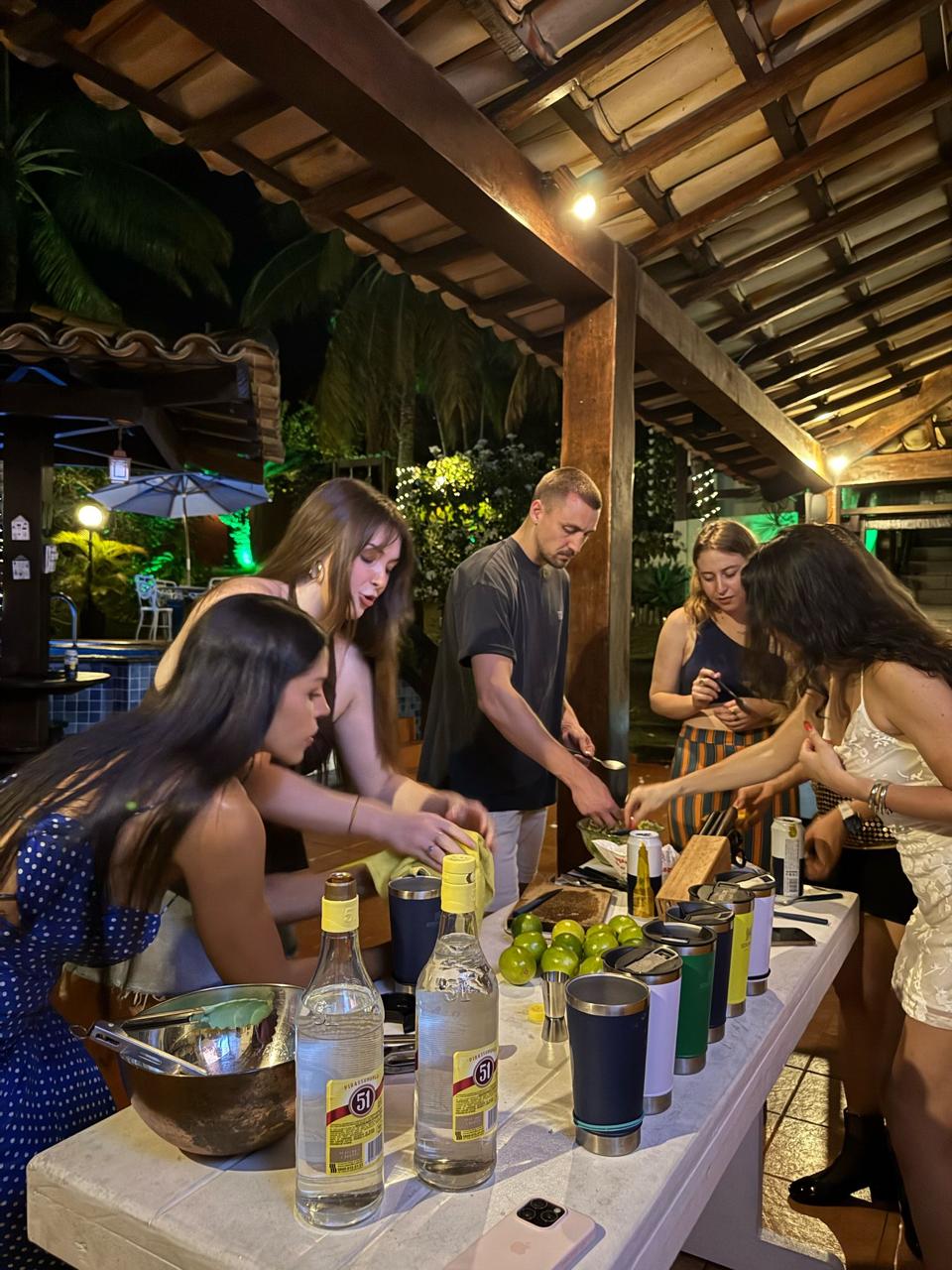 Guests making caipirinhas together at a table at night