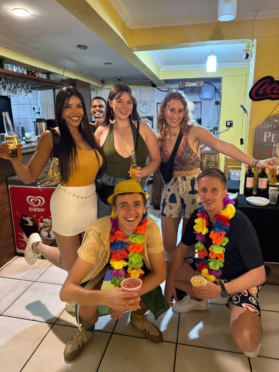 The whole group together at a bar with drinks and flower garlands